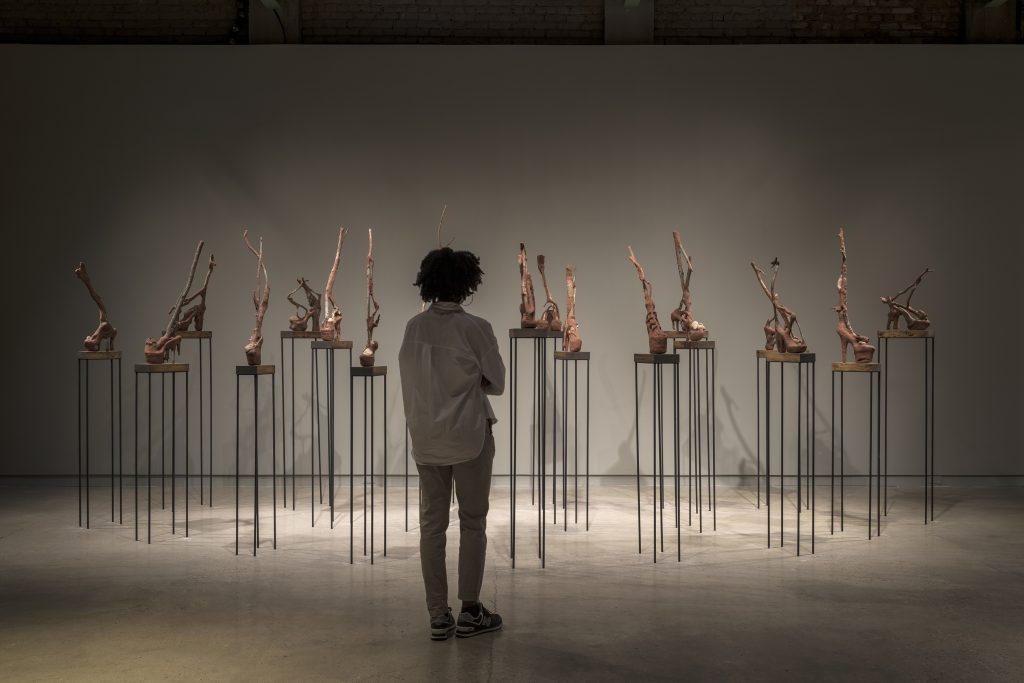 Wangechi Mutu "Heeler I–XIX," 2016 Red soil, paper pulp, wood glue, rocks, acrylic shoes, and wood Dimensions variable  Installation view, "Wangechi Mutu," The Contemporary Austin – Jones Center on Congress Avenue, Austin, Texas, 2017 Artwork © Wangechi Mutu Courtesy the artist and Gladstone Gallery, New York and Brussels Image courtesy The Contemporary Austin Photograph by Colin Doyle