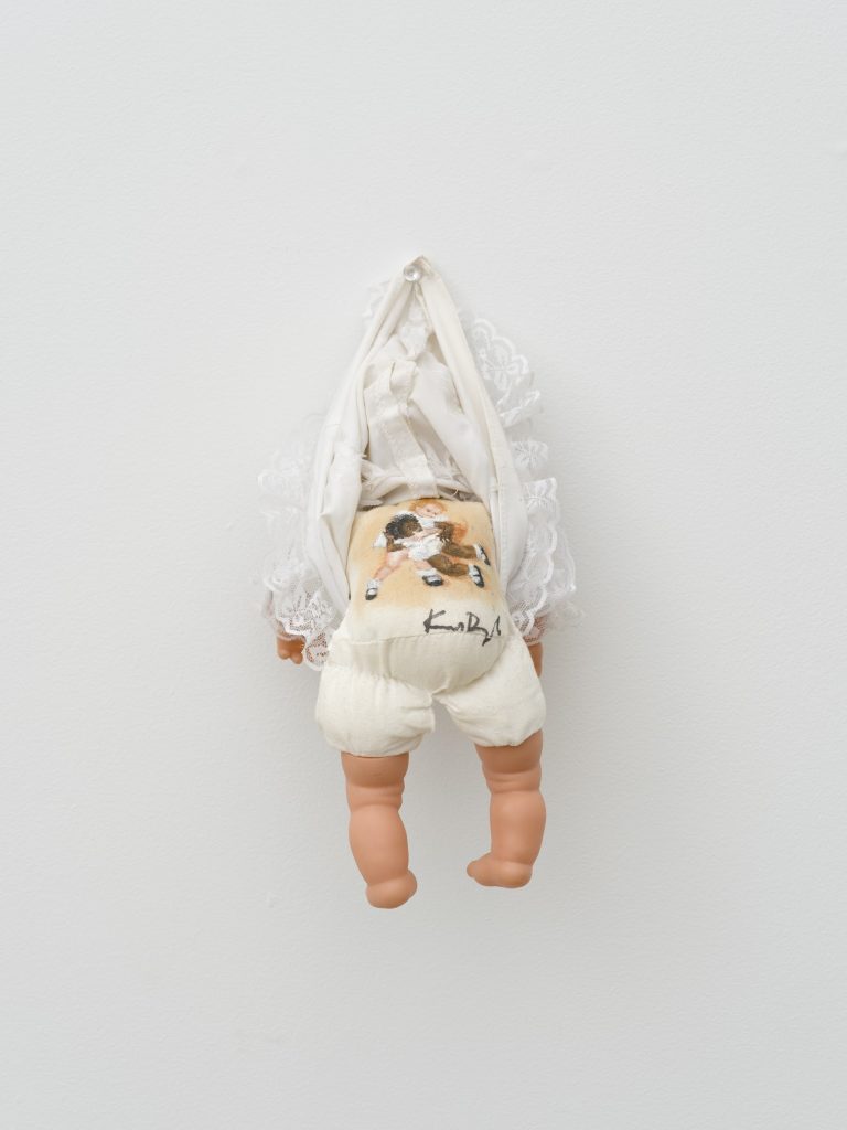 This image depicts an artwork by Kim Dingle titled "Toy Baby." This artwork was created in 1993 and measures 11" x 5" x 4" [HxWxD] (27.94 x 12.7 x 10.16 cm). Its medium is Oil on toy baby.