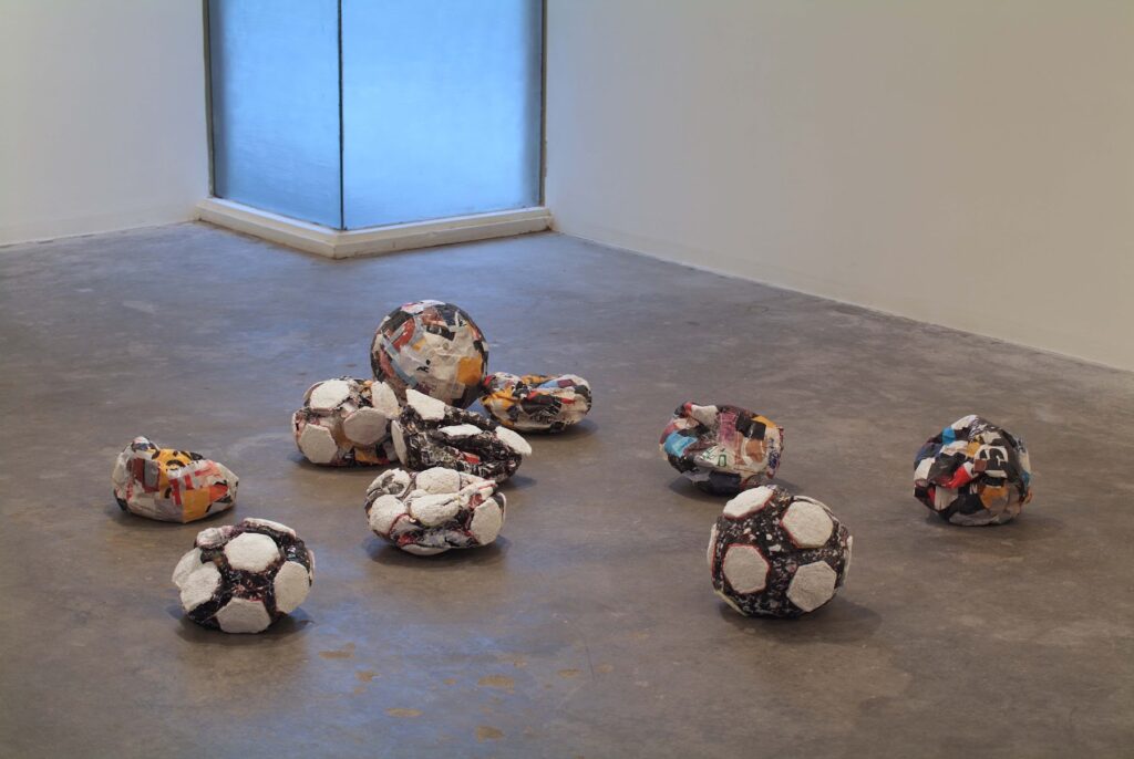 This image depicts an artwork by Mark Bradford titled "Untitled (Crushed Soccer Balls)." This artwork was created in 2004 and measures Approx: 12" x 12" x 6" [HxWxD] (30.48 x 30.48 x 15.24 cm) each. Its medium is Paper maché.