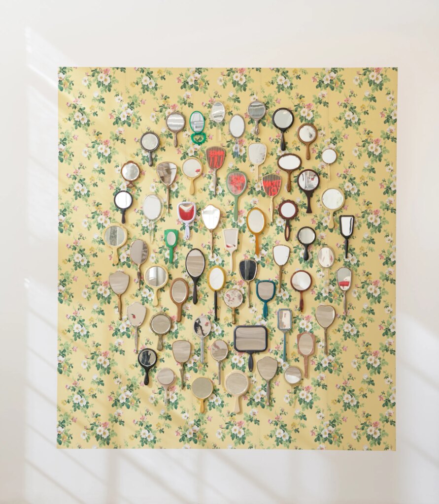 This image depicts an artwork by Genevieve Gaignard titled "Do You Only Want to See What You Believe?." This artwork was created in 2022 and measures 102" x 90 ¹⁄₂" x 1" [HxWxD] (259.08 x 229.87 x 2.54 cm). Its medium is Found mirrors, vintage wallpaper.